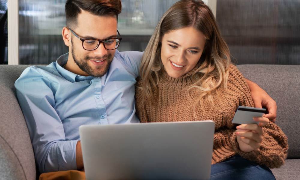 Gelukkig stel op de bank met laptop en pinpas